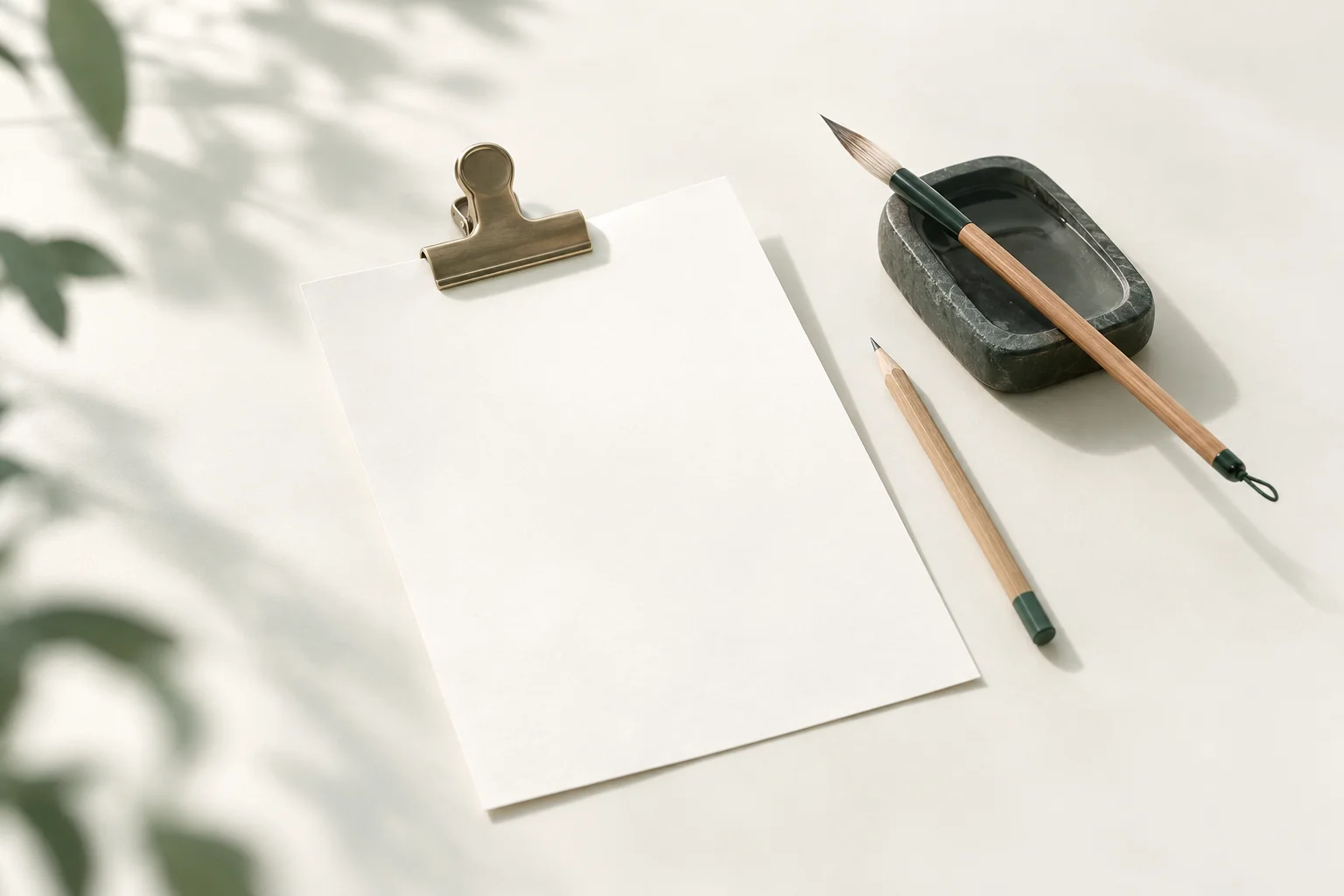 Illustration: loses Blatt mit einer großen Klemme aus Messing, daneben ein Kalligrafiepinsel auf einem Tuschestein und ein Bleistift